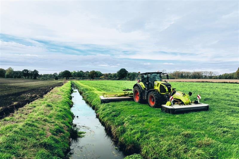 Claas Traktor bei der Feldarbeit an einem kleinen Graben mit Wasser
